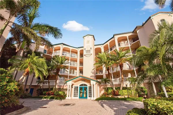 a front view of a multi story residential apartment building with yard and parking space