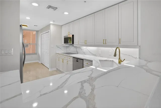 a kitchen with granite countertop white cabinets and a sink