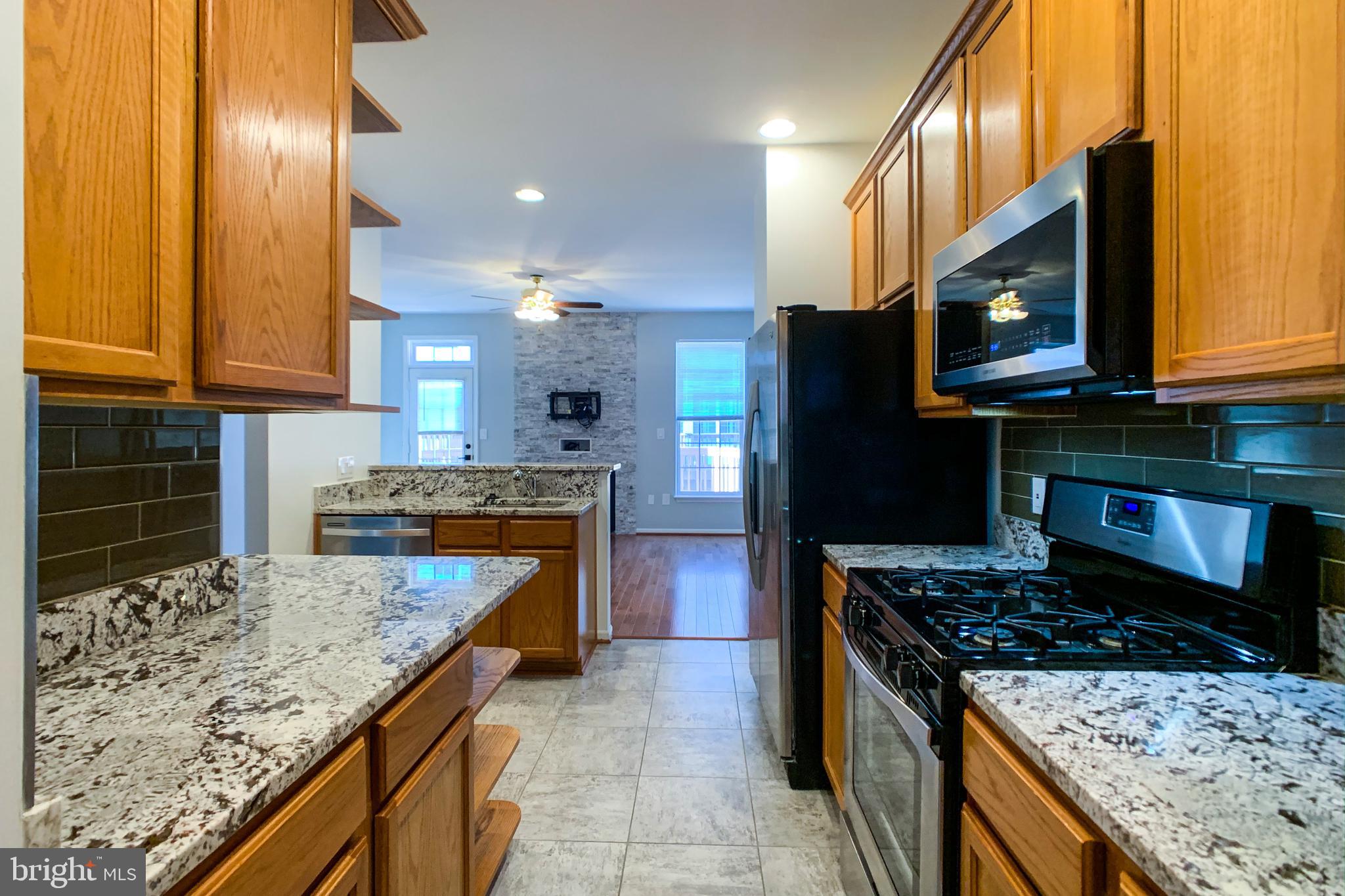 6988 Cromarty Drive Alexandria, VA 22315 - Photo 30 of 62 a kitchen with stainless steel appliances granite countertop a stove a sink and a microwave