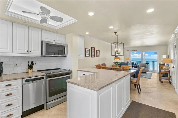a kitchen with appliances a sink a counter top space cabinets and a window