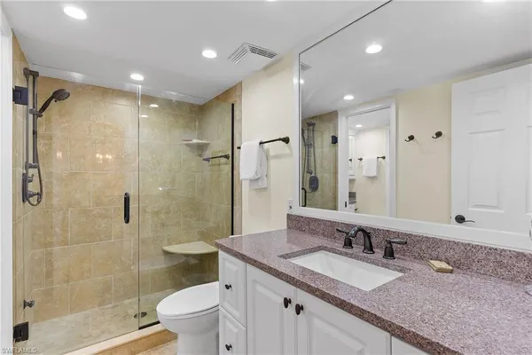 a bathroom with a granite countertop sink a toilet a large mirror and shower