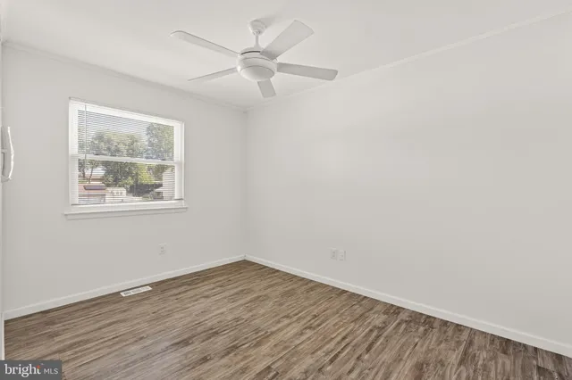 a view of an empty room with wooden floor and closet