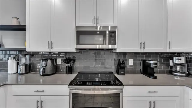 a kitchen with granite countertop white cabinets and stainless steel appliances