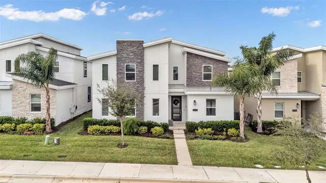a view of a white house next to a yard with big trees