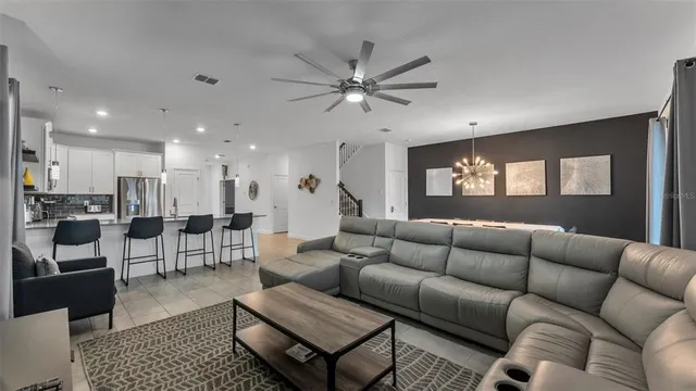 a living room with furniture kitchen view and a chandelier