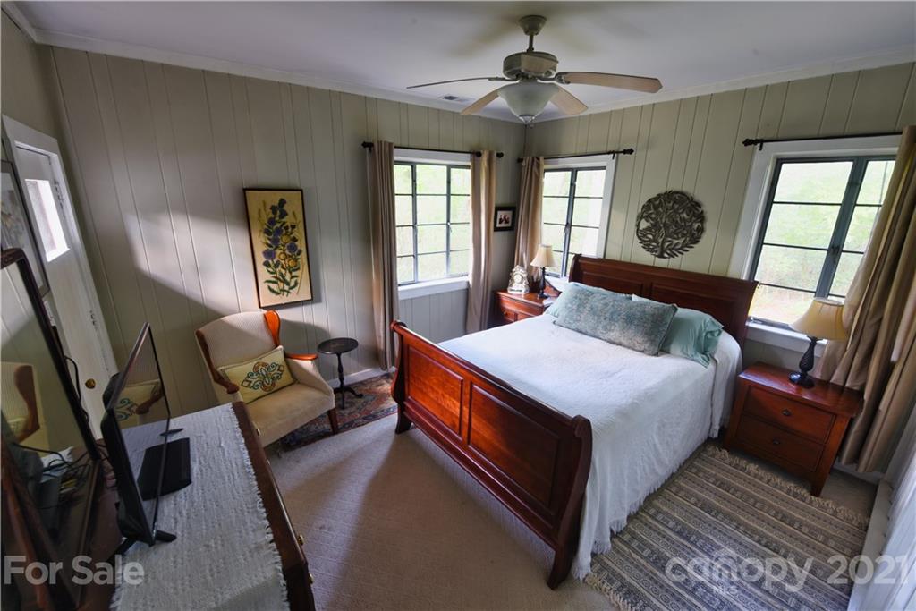 528 Wilderness Road Tryon, NC 28782 - Photo 19 of 29 a bedroom with a bed a mirror on dresser and a large window
