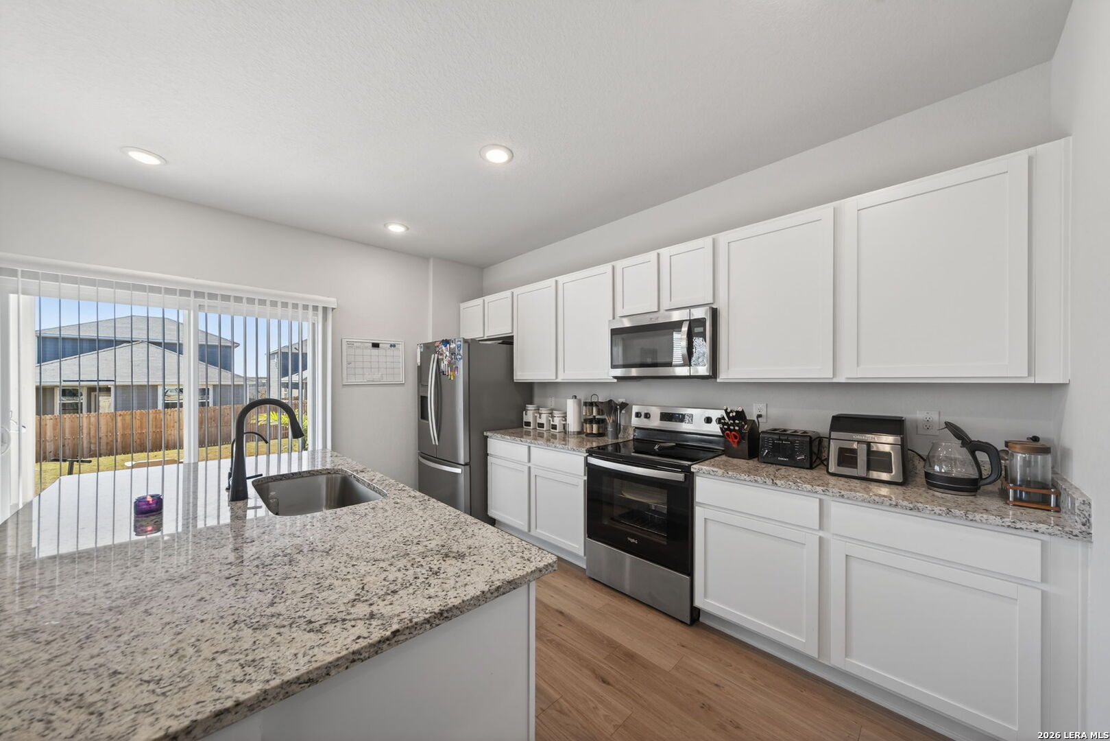 4238 Danforth Street New Braunfels, TX 78130 - Photo 9 of 21 a kitchen with stainless steel appliances granite countertop a sink a stove top oven a refrigerator with white cabinets and wooden floor