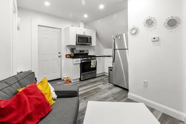 a living room with stainless steel appliances furniture a refrigerator and a window