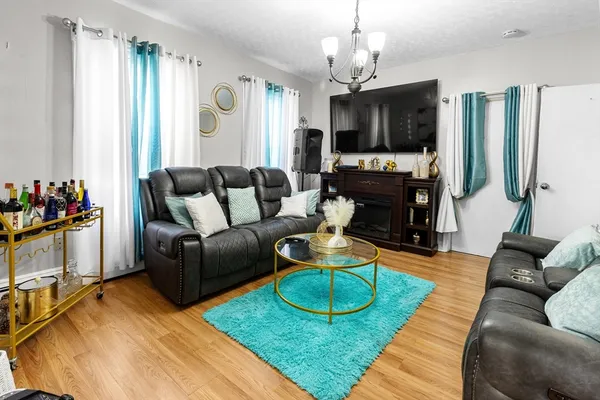a living room with furniture a flat screen tv and a chandelier