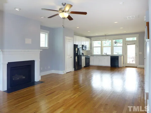 an empty room with wooden floor a fireplace and windows