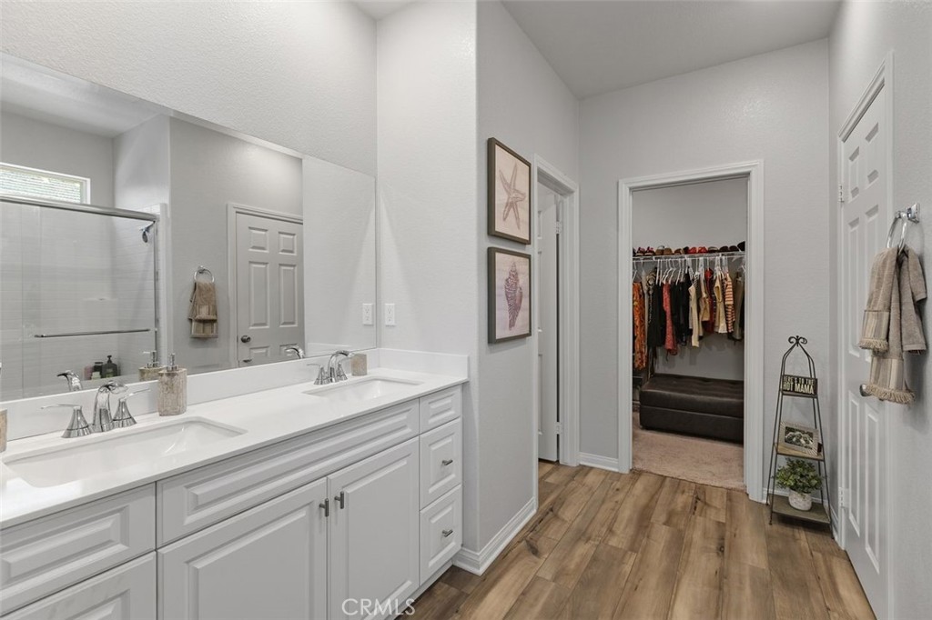 7598 Orangebrook Cove Riverside, CA 92507 - Photo 23 of 45 Primary ensuite bathroom dedicated grooming area features a elegant dual vanity with updated fixtures, polished stone countertops, integrated lighting and spacious closet.