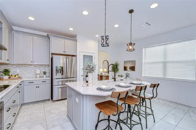 a kitchen with stainless steel appliances kitchen island granite countertop a sink a stove a dining table and chairs