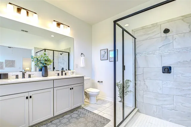 a spacious bathroom with a double vanity sink toilet and shower