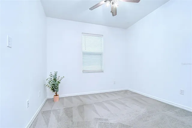 an empty room with a chandelier fan and windows