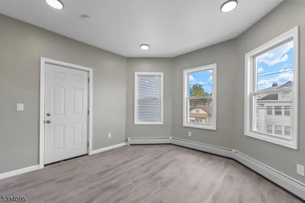 a view of an empty room with a window and wooden floor