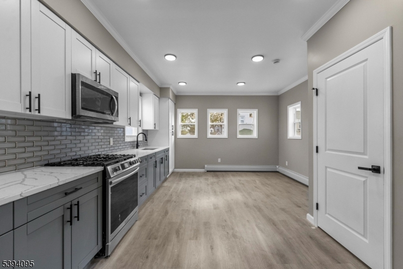 1033 East 23rd Street, Unit 2 Paterson, NJ 07513 - Photo 6 of 21 a large kitchen with stainless steel appliances granite countertop a stove and a sink