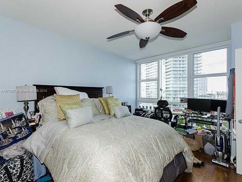 400 Alton Road, Unit 1011 Miami Beach, FL 33139 - Photo 10 of 13 a bedroom with bed a large window and a chandelier