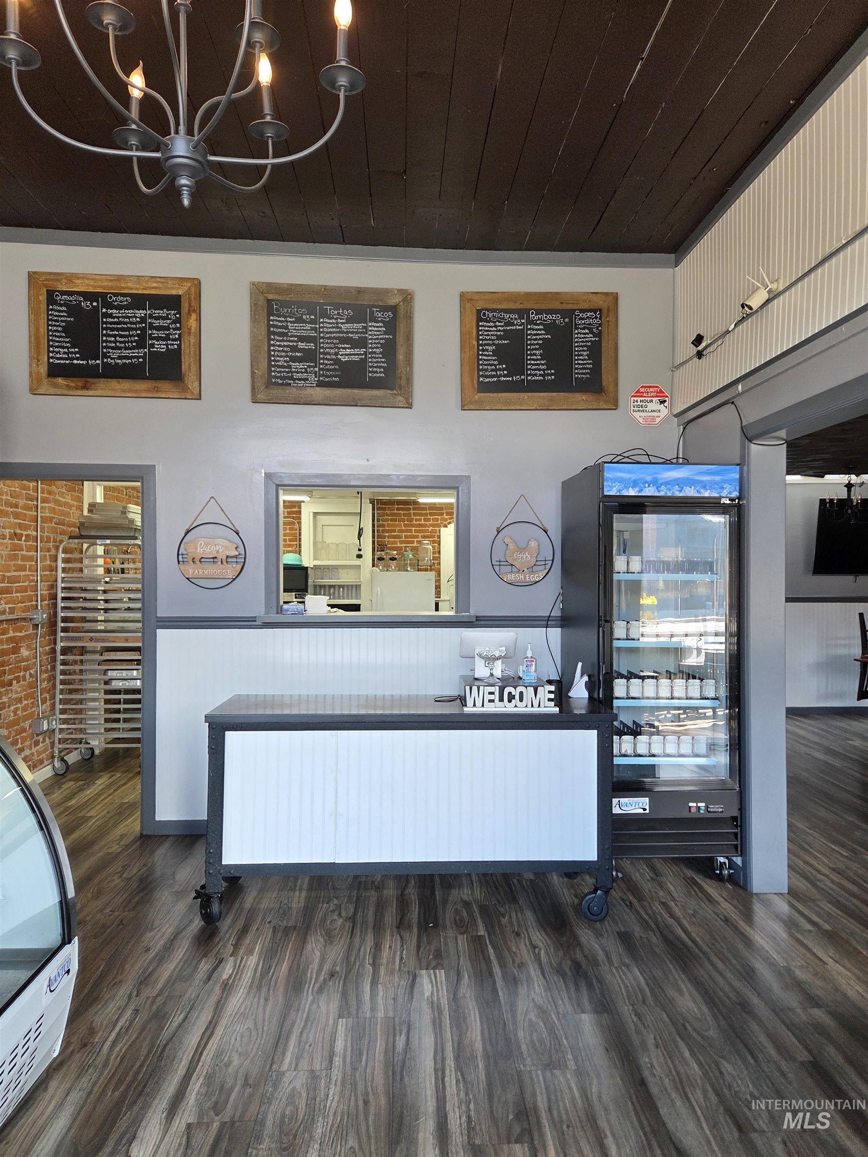 Retail counter area featuring wood-finish flooring, exposed wood beam ceiling, and a built-in service counter with white paneling