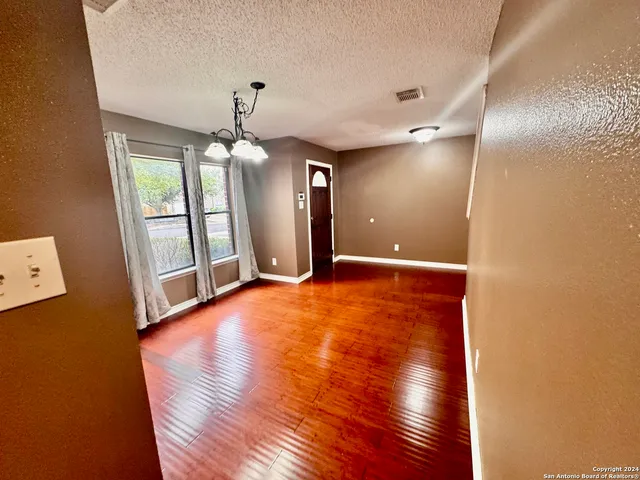 a view of an empty room with window and wooden floor