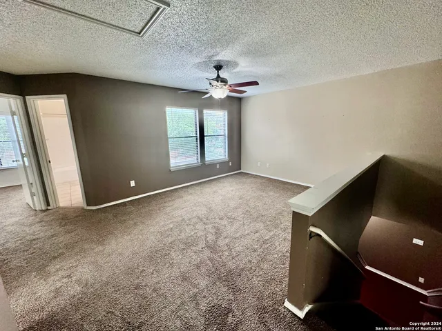 an empty room with windows and fan