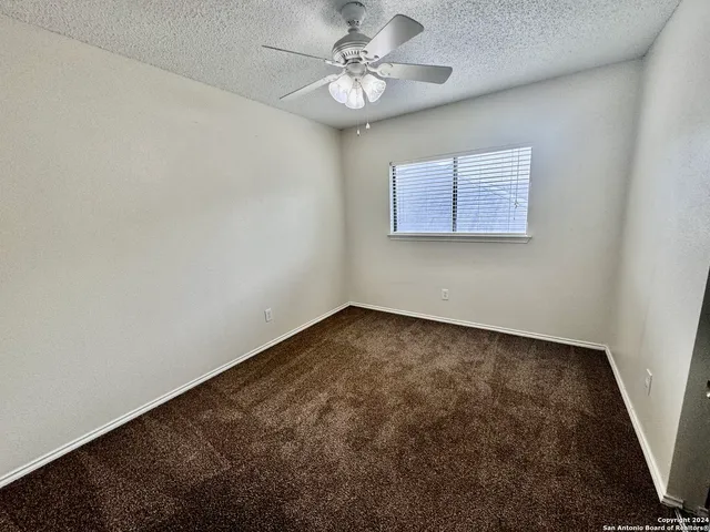 an empty room with a chandelier fan and windows