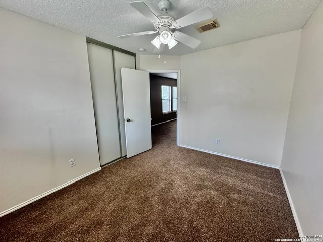 an empty room with closet and a ceiling fan