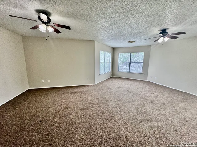an empty room with windows and fan