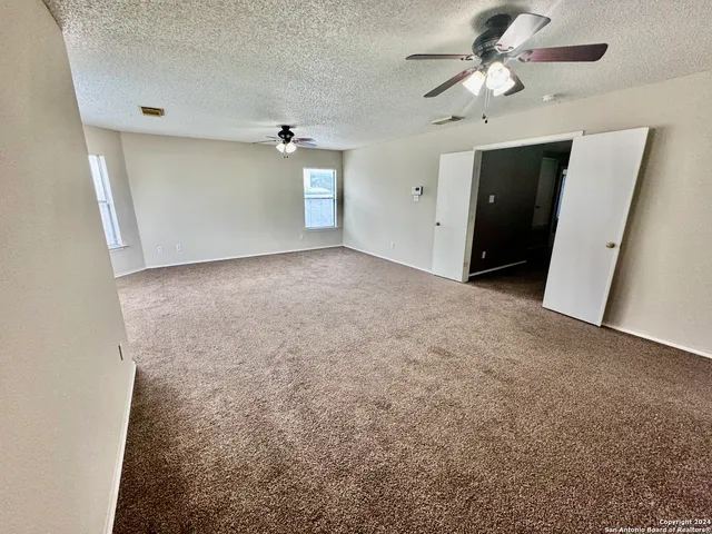 a view of a big room with a ceiling fan and a window