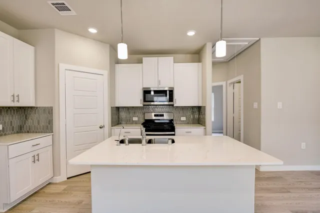 a kitchen with kitchen island a sink stainless steel appliances and cabinets