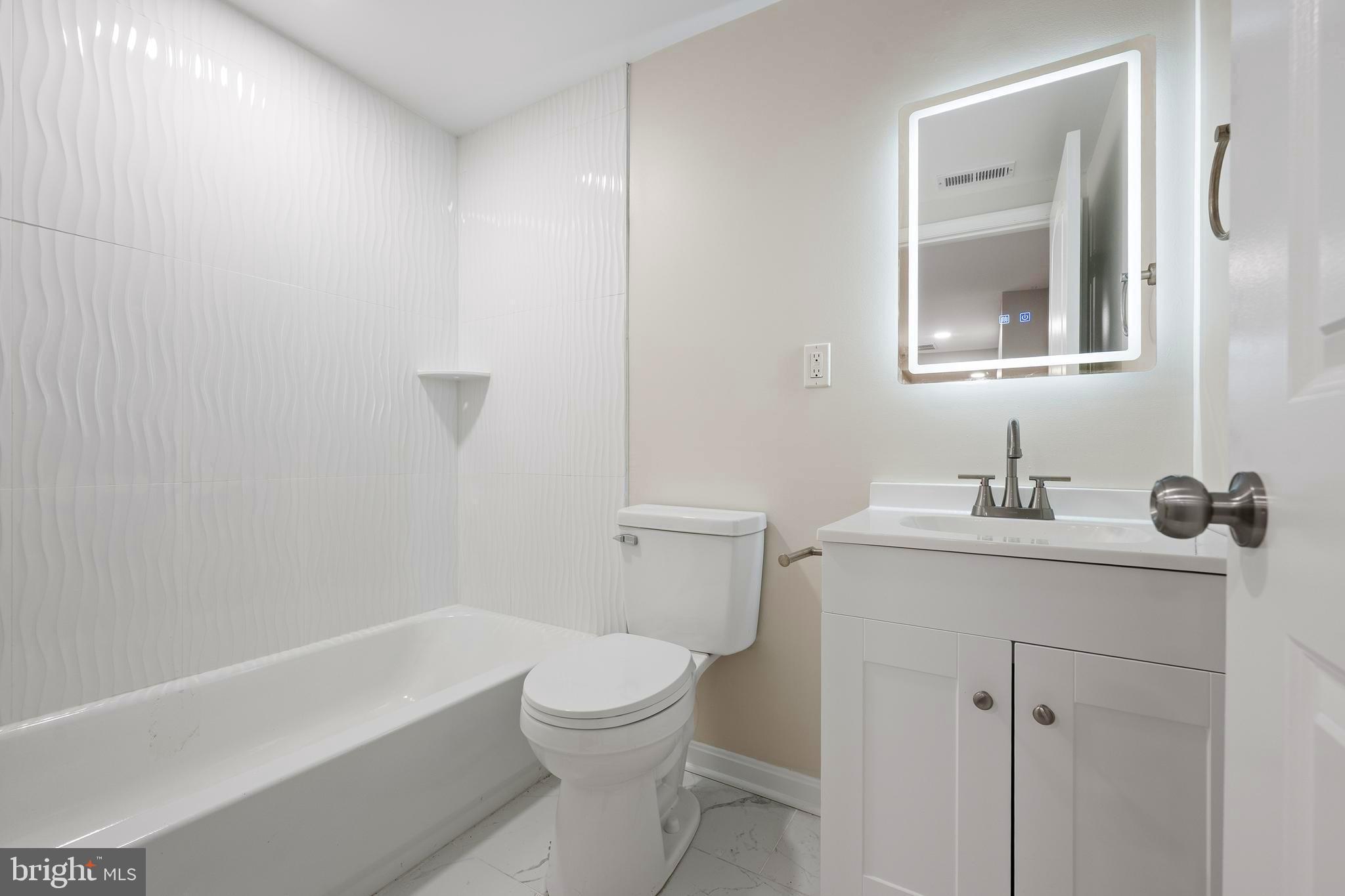 1358 Towson Street Baltimore, MD 21230 - Photo 44 of 51 a bathroom with a toilet a sink a mirror and vanity