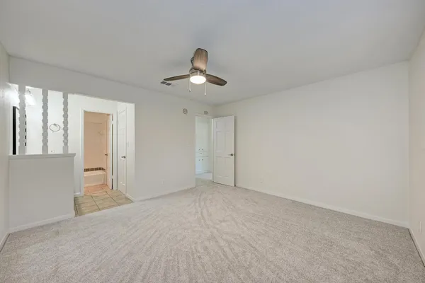 a view of an empty room and chandelier fan