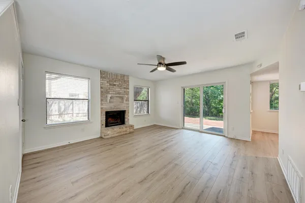 a view of an empty room with a window and wooden floor
