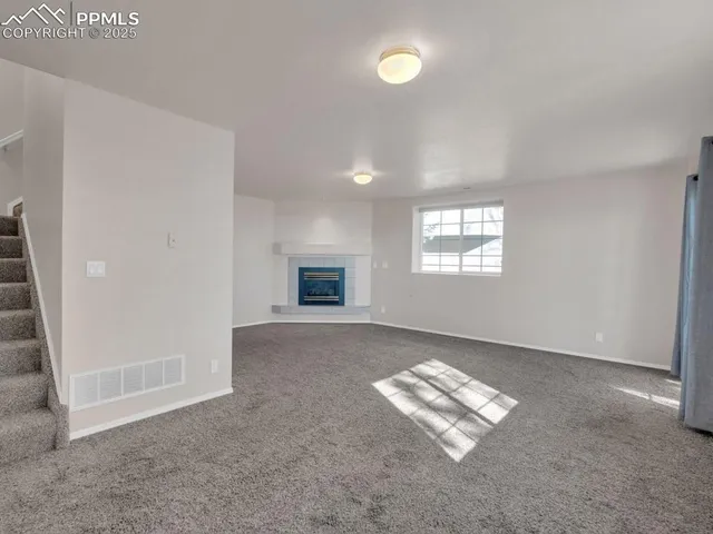 an empty room with windows and fireplace