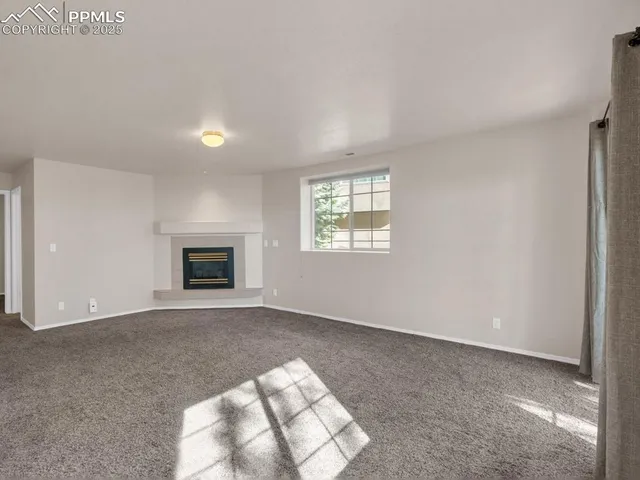 an empty room with windows and fireplace