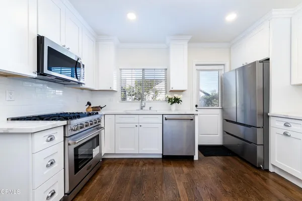 a kitchen with white cabinets stainless steel appliances and wooden floor