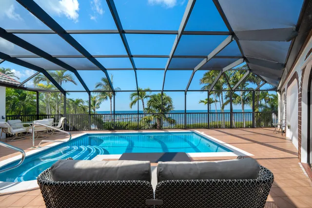 a view of a table and chairs under an umbrella in front of a house