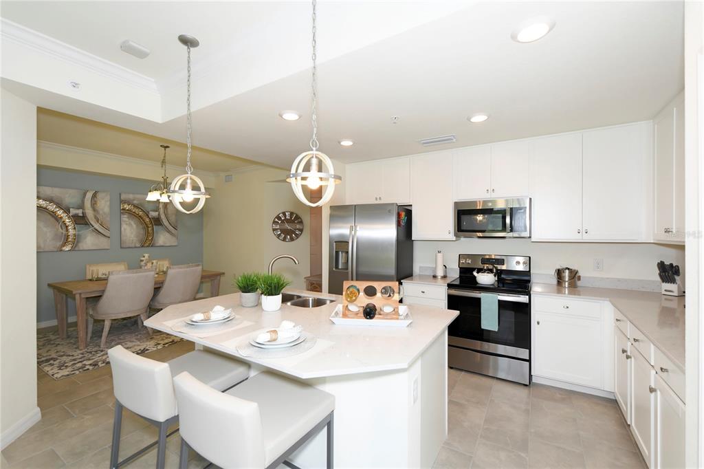 17810 Gawthrop Drive, Unit 101 Lakewood Ranch, FL 34211 - Photo 16 of 53 a kitchen with stainless steel appliances a kitchen island a stove a table and chairs in it