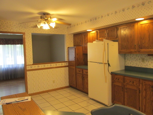 708 South Cooper Road New Lenox, IL 60451 - Photo 4 of 24 a view of a refrigerator in kitchen and an empty room with wooden floor