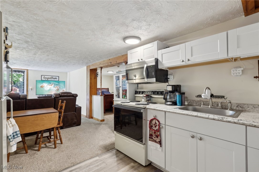 6672 Ross Road Madison, OH 44057 - Photo 45 of 50 Kitchen with a textured ceiling, white cabinetry, white electric range, light carpet, and sink