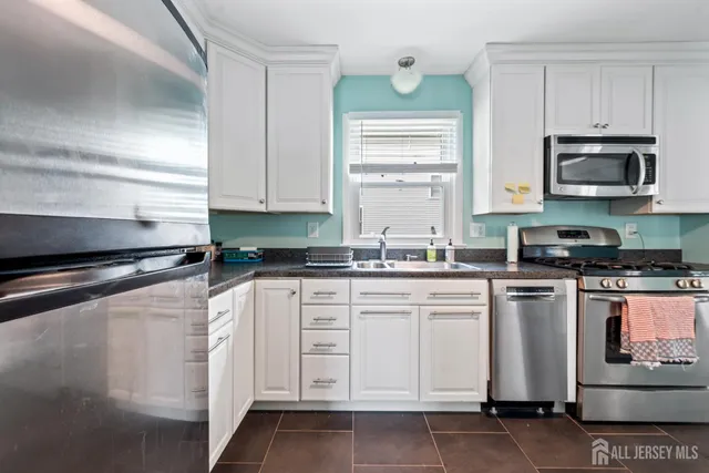 a kitchen with white cabinets white stainless steel appliances and sink