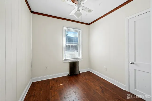 an empty room with wooden floor chandelier fan and windows