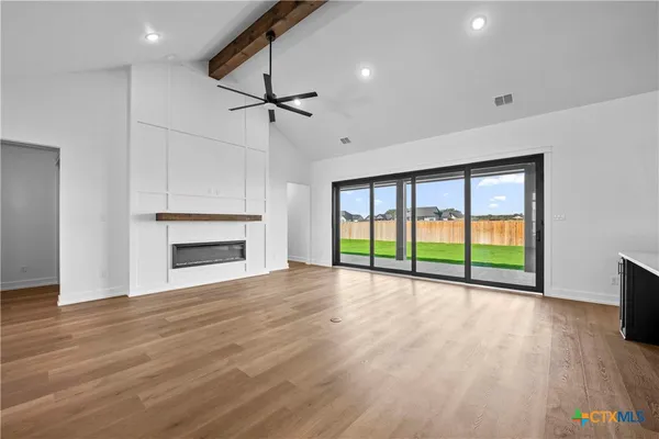 a view of an empty room with wooden floor fireplace and a window