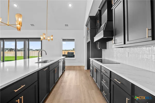 a kitchen with stainless steel appliances granite countertop a sink a stove and a wooden floors