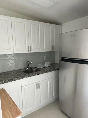 a kitchen with granite countertop a sink and a refrigerator