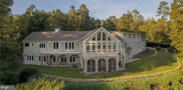 a aerial view of a house next to a yard with plants and large trees