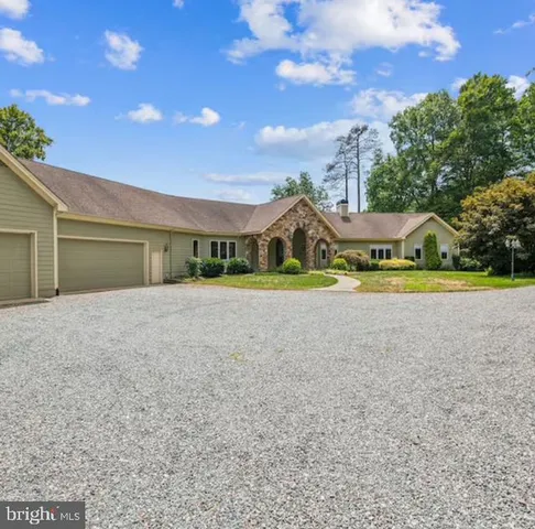 a view of yellow house with a big yard and plants