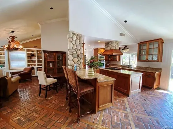 a kitchen with stainless steel appliances kitchen island granite countertop a table chairs in it and a wooden floors