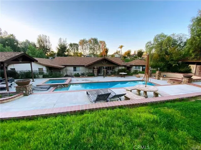 a view of a swimming pool and lounge chairs in back yard of the house