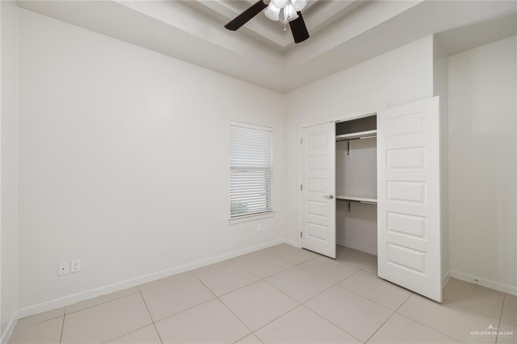 1716 West Garrison Drive, Unit 2 Pharr, TX 78577 - Photo 11 of 17 Unfurnished bedroom featuring light tile patterned floors, a tray ceiling, a closet, and ceiling fan