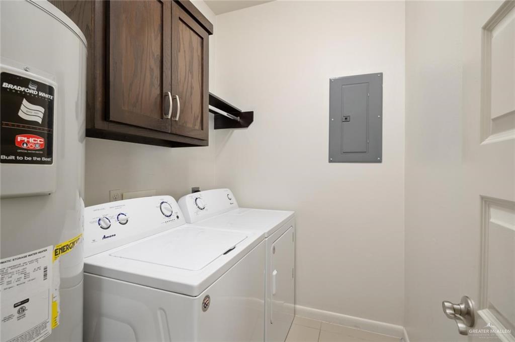 1716 West Garrison Drive, Unit 2 Pharr, TX 78577 - Photo 13 of 17 Laundry area with water heater, electric panel, cabinet space, washing machine and dryer, and light tile patterned flooring